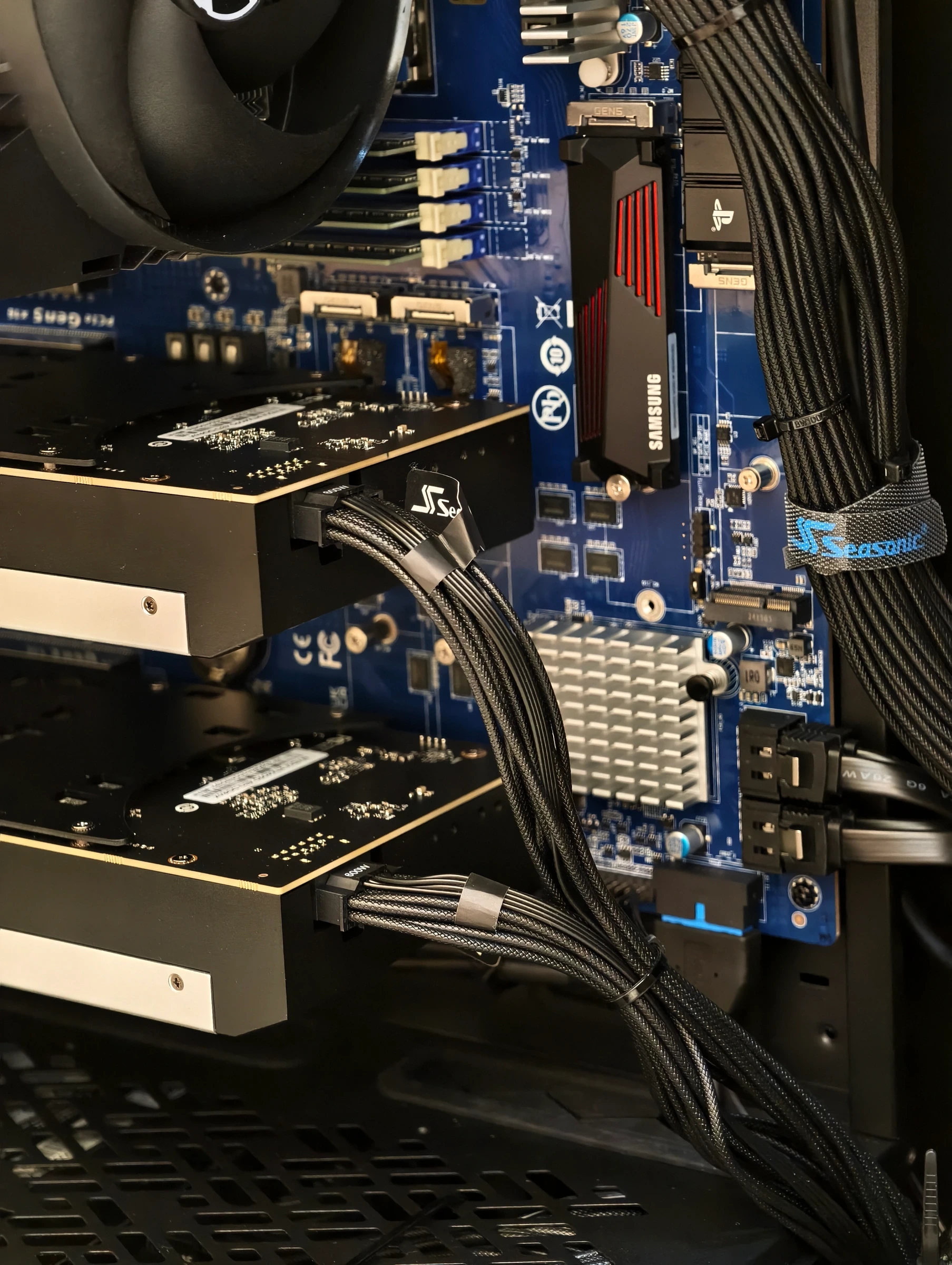 Interior view with sleeved power cables routed clear of the GPUs, past the motherboard and an NVMe drive under its heatsink