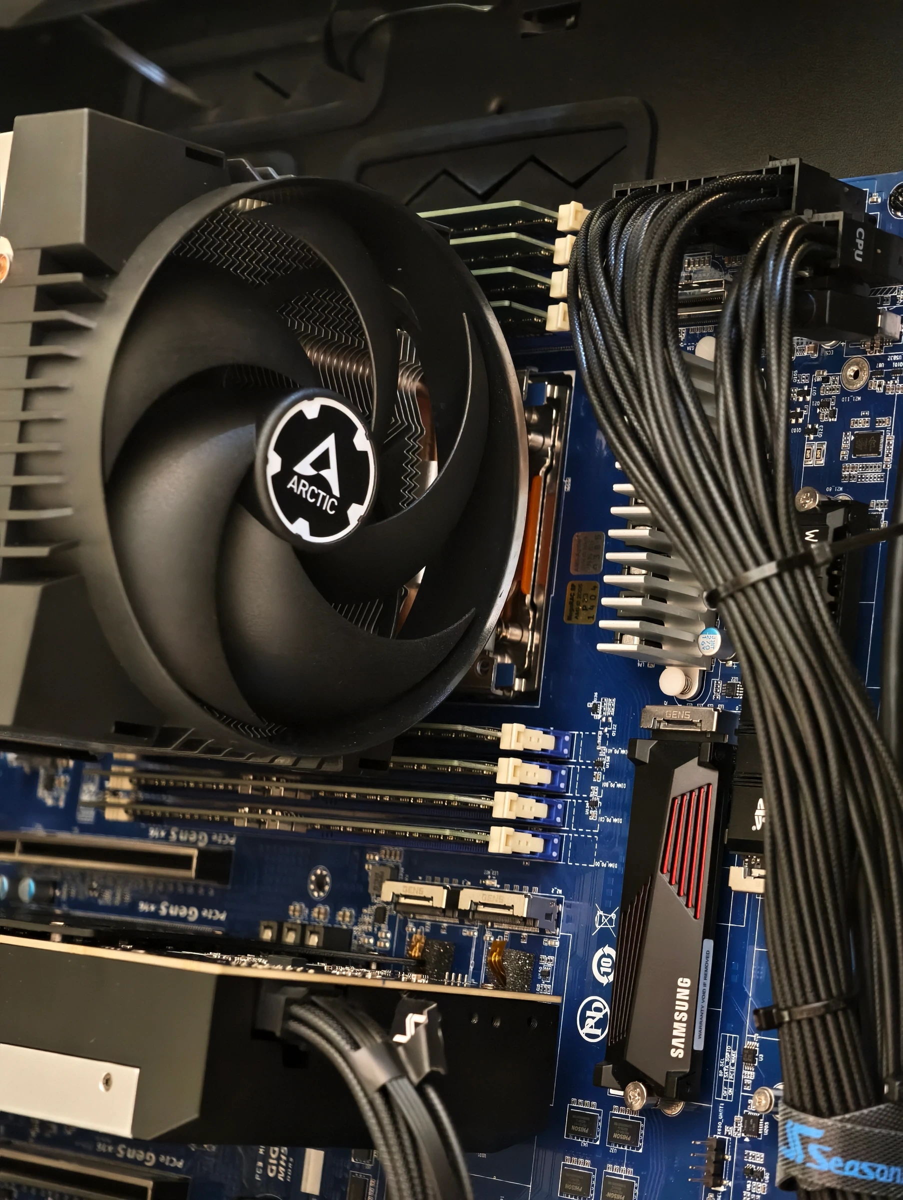 A large air CPU cooler with exposed copper heat pipes beside a 140mm case fan, with no liquid loop anywhere in the build